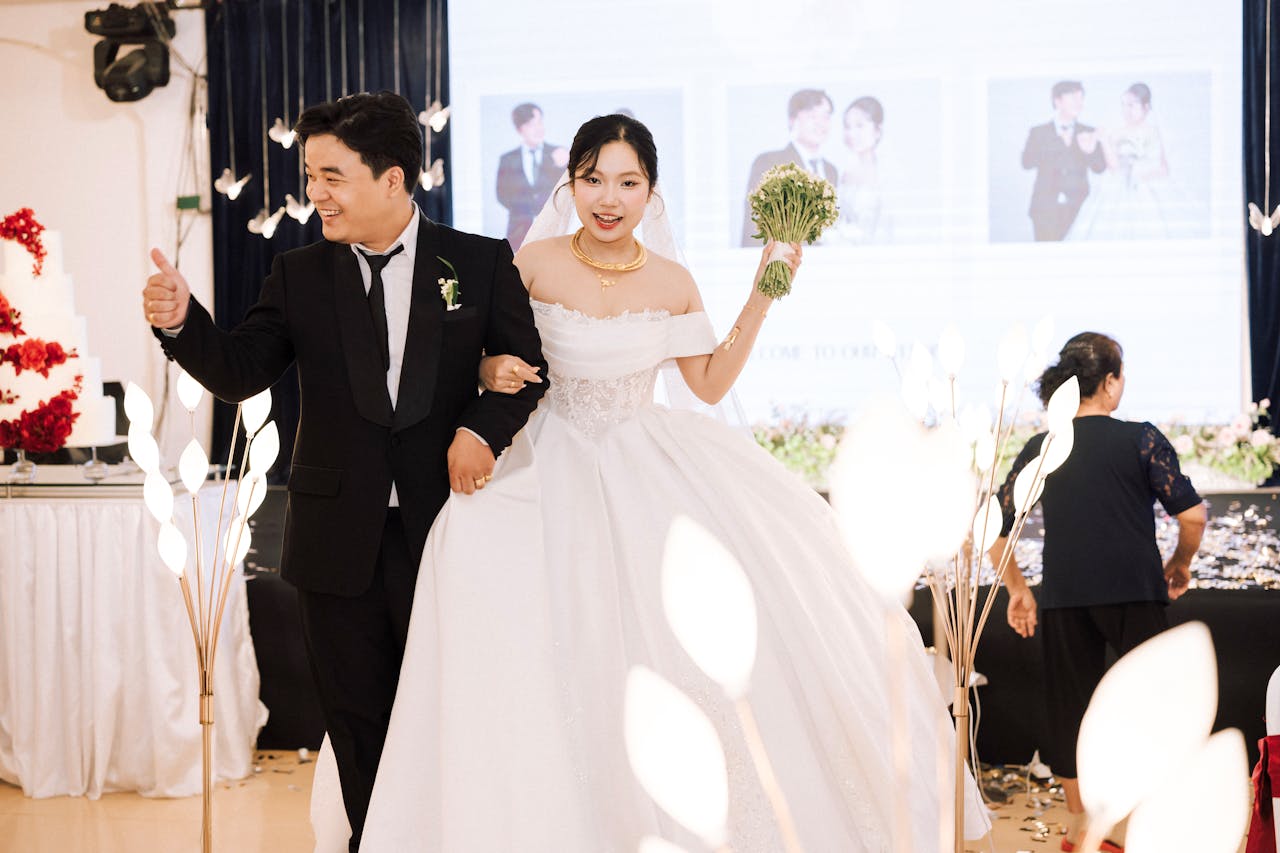 A happy bride and groom celebrating their wedding indoors with cheerful expressions and elegant attire.